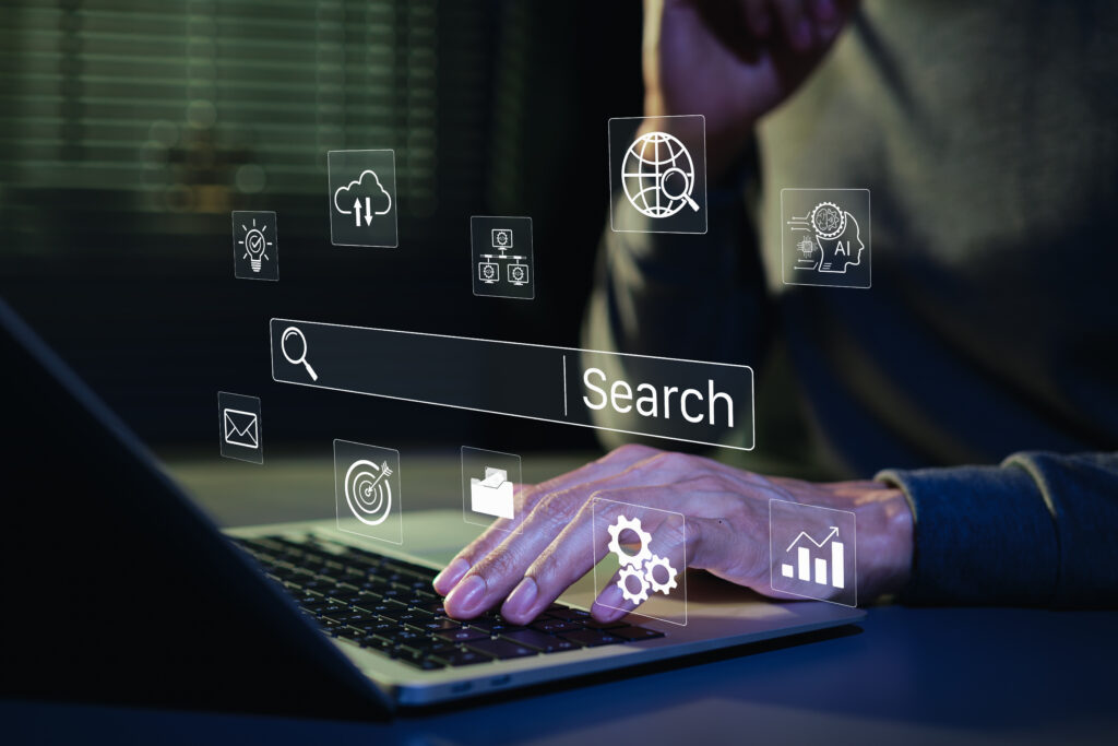 Hand on a laptop with a search bar and analytics icons overlaid