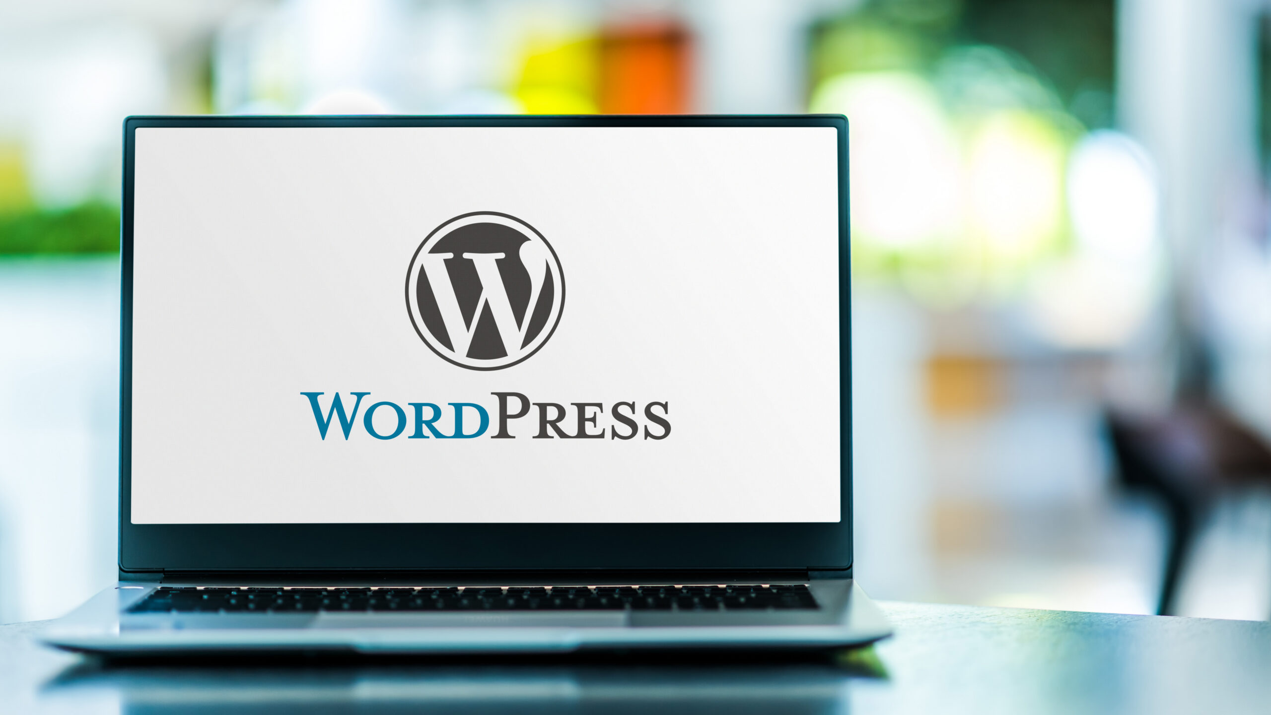 Laptop on a desk showing the WordPress logo on its screen